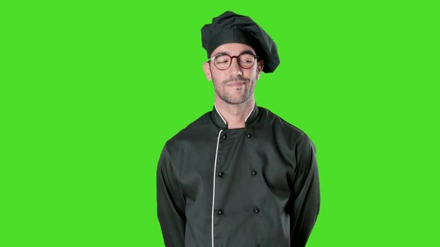 Confident young chef looking against green background