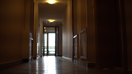 Low angle walk move through long, empty dark building corridor, cinematic steadicam shot