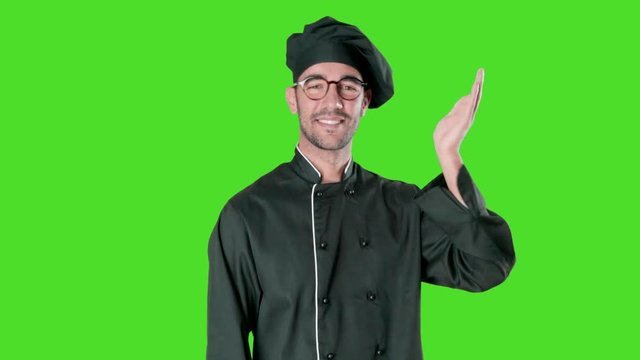 Happy young chef greeting against green background