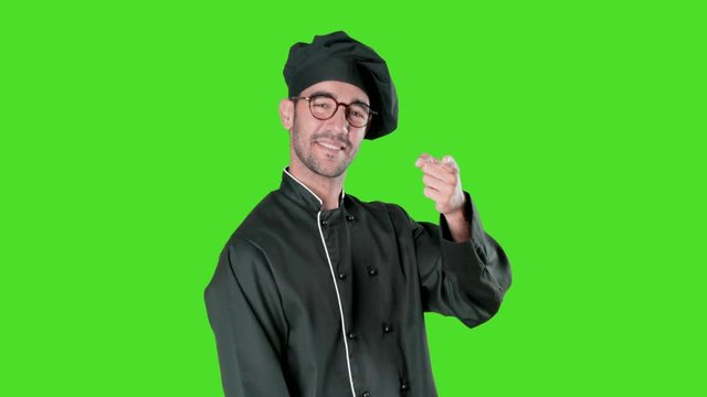 Confident young chef pointing to you with his finger against green background