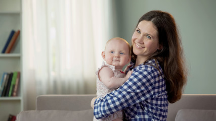 Pretty young mother and cute baby daughter hugging and smiling, happy future