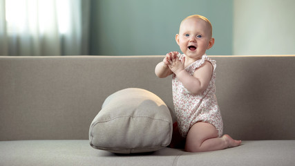 Healthy baby playing in good mood, clapping hands and laughing, happy childhood