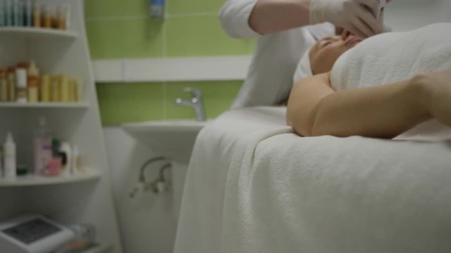 Relaxed woman gets ultrasound facial cleansing treatment in cosmetology salon
