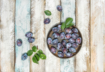 Plum fruits green leaves rustic wooden background