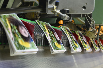 Brochure and magazine stitching process. Close-up of the  offset conveying process of a...
