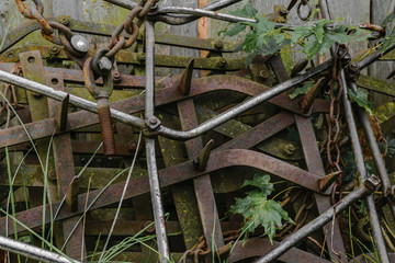 Very old and rusty harrows places near barn wall at countryside