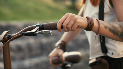 Woman legs walking beside riding bike on city road. Woman feet and bicycle wheel