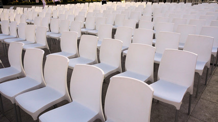 Many white chairs. Rows of plastic white chairs - seats for spectators or fans.