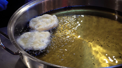 Chief makes donuts. Donuts fry in boiling oil.