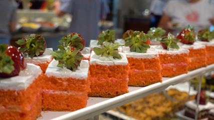 Restaurant Buffet. In the foreground there are plates with dessert. In the background, defocused citizens choose food.