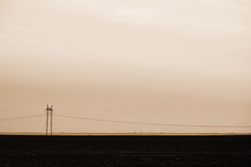 Power lines on background of sky close-up. Silhouette of electric pole with copy space in sepia...