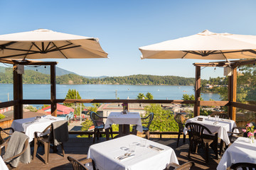 A restaurant patio with tables set overlooking Gibsons, BC, on a bright sunny day.