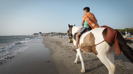 Durres, Albania - circa Aug, 2017: Handsome young boy riding a horse on a tropical beach