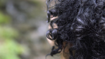 Close up portrait of hiker woman with curly hair looking up at forest observing a Route in nature