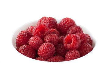 A bowl of red raspberries on a white background