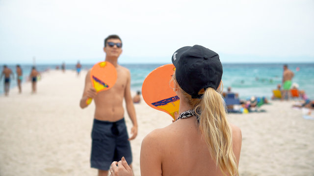 Couple in bikini playing beach-tennis, cinematic view