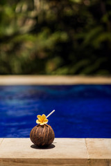 Coconut drink with yellow flower at poolside