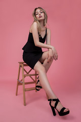 Naklejka premium beauty fashion portrait of young female on a pink background in black dress