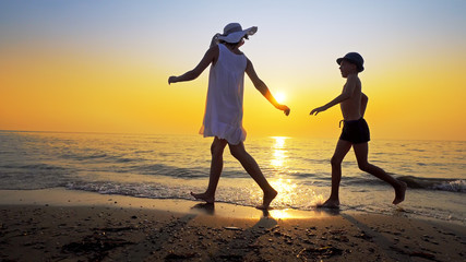 Tourism and travel vacation. Adorable family having fun on beach against sunset. Mother and son walk on beach an play, cinematic steadicam shot