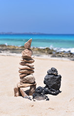 Fototapeta na wymiar Stack of balanced stones in a white sand beach in Fuerteventura Island, Canary Islands, Spain