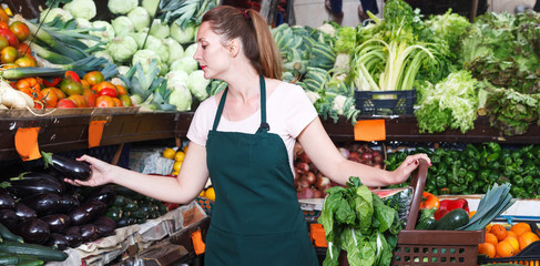 Saleswoman holding aubergine in market