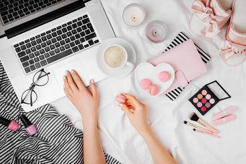 Young woman freelancer working with laptop in bed, flat lay,  top view