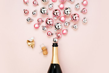 Champagne bottle with pink and silver christmas balls. Flat lay, top view trendy holiday concept.
