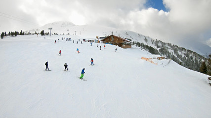 POV from ski lift with aerial view of skiers on slope and distant snow covered mountain peaks, SLOW MOTION