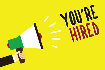 Text sign showing You re are Hired. Conceptual photo New Job Employed Newbie Enlisted Accepted Recruited Man holding megaphone loudspeaker yellow background message speaking loud