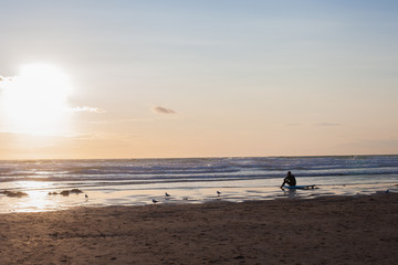 Surfer on the ocean beach at sunset