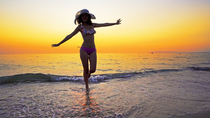 Sexy teen in bikini and hat go out of sea water at sunset, Summer vacation concept
