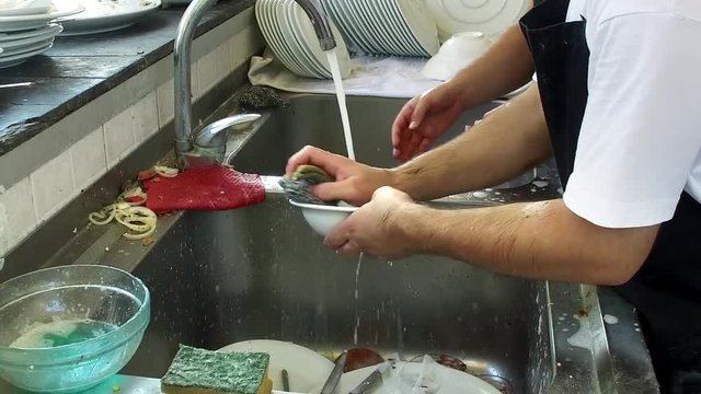 Man washing dishes in restaurant kitchen, slow motion