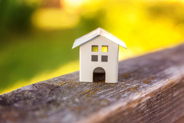 Obraz na płótnie Canvas Miniature white toy model house in wooden background near green backdrop. Eco Village, abstract environmental background. Real estate mortgage property insurance dream home ecology concept