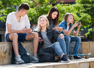 Company of carefree teenagers sitting in park