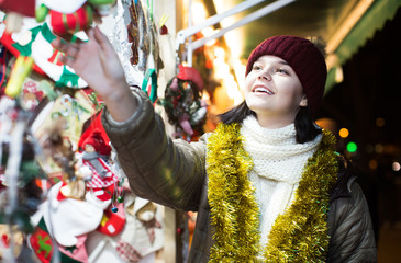 girl choosing Christmas decoration at market