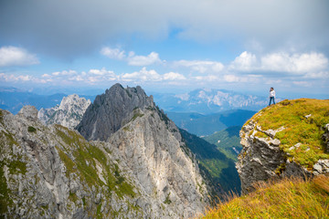 Obraz premium Young woman on cliff in Mangart saddle in Slovenia