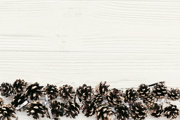 christmas flat lay. modern christmas layout with golden pine cones border on white wood, top view with space for text. holiday mockup greeting card. stylish winter flatlay