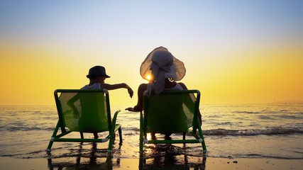 Fototapeta na wymiar Family, mother and son having fun sitting on beach at sunset