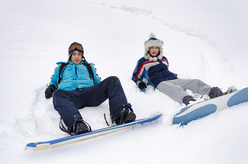 Fototapeta na wymiar Two happy snowborder skiers laying on snow
