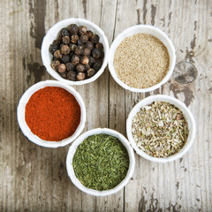 Various spices in bowl over rustic white wooden background . Top view. Square image.