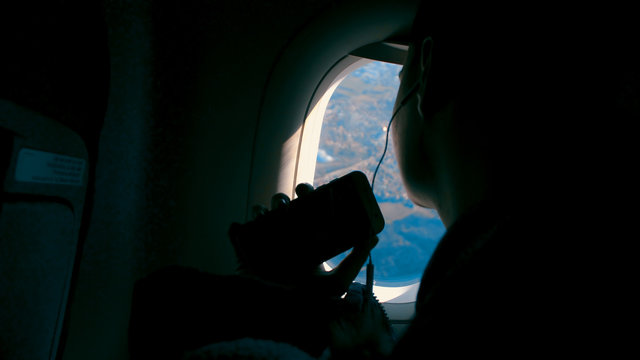 Happiness of asian girl with headphone listening music and taking pictures with smartphone and smiling looking on the airplane window