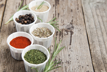Various spices on wooden rustic background: rosemary, paprika, black pepper. Top view. Copy space.