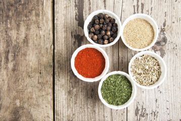 Various spices on wooden rustic background: rosemary, paprika, black pepper. Top view. Copy space.