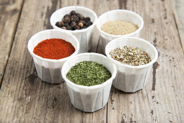 Various spices on wooden rustic background: rosemary, paprika, black pepper. Top view.