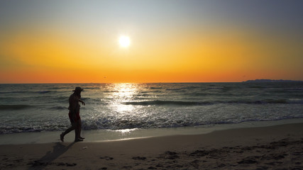 Fototapeta na wymiar Loving Couple Holding Hands Beach Vacation Sunset - Young ethnic couple holding hands watching sunset on beach vacation