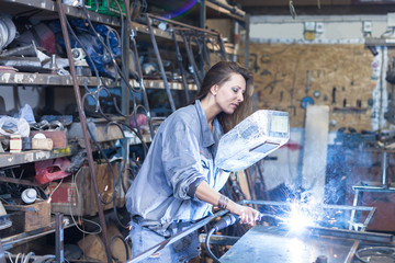 young woman welding in a workshop - obrazy, fototapety, plakaty