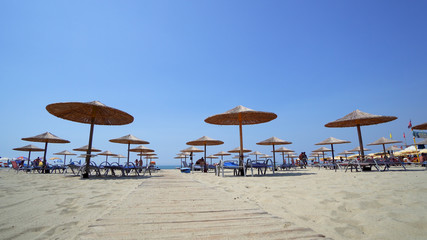 Empty Sunny Beach with Umbrellas, Sun Beds on the Ionian Sea. The coastal resort line, where people relax and sunbathe