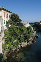 Fototapeta na wymiar Bosnia: lo skyline di Mostar, la città vecchia sul fiume Narenta, con un palazzo esempio dell'architettura austro-ungarica costruito durante il periodo della dominazione austro-ungarica