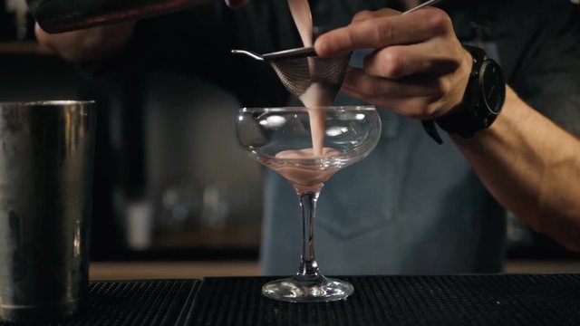 Young professional bartender preparing cocktails outside Close up Slow motion pouring shaker lemonade