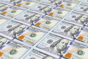 Large surface covered with US cash notes. High angle view of US hundred cash notes carefully spread out on the desk